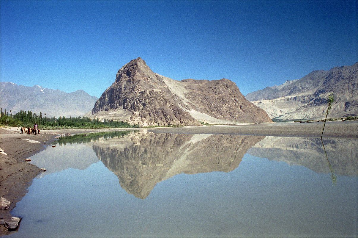 08 Skardu Khardong Hill And Kharpocho Fort Reflected In The Indus River The Khardong Hill with the Kharpocho Fort is beautifully reflected in the calm Indus River in Skardu (2286m). Skardu is the district headquarters of Baltistan, situated on the banks of the mighty Indus River, just 8 km (5 miles) above its confluence with the Shigar River. The Indus barely seems to move across the immense, flat Skardu valley, 40km long, 10 km wide and carpeted with sand dunes. There are several beautiful blue lakes nearby, including Satpara, and Upper and Lower Kachura.